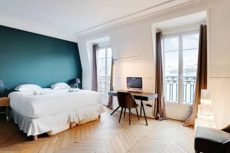 une chambre avec un grand lit et un bureau avec un ordinateur dans l'établissement Appartement chic au cœur de Paris Montorgueil 2BDR, à Paris