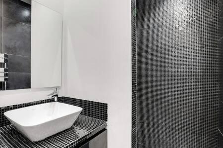 une salle de bain en noir et blanc avec un lavabo et un miroir dans l'établissement Appartement chic au cœur de Paris Montorgueil 2BDR, à Paris