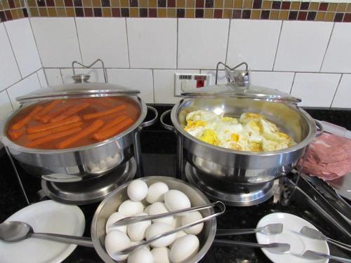 a stove with two pots of food and eggs on it at Hotel Neon - próximo a 25 de março, Bom Retiro e Brás, á 2min do mirante Sampa SKY e pista de skate Anhangabaú in Sao Paulo