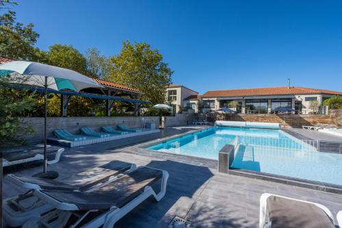 a swimming pool with lounge chairs and an umbrella at Côté Océan Resort in Angoulins