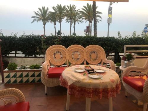 a table with four chairs and a table with food on it at Apartamento lujoso en primera linea de playa in Castell de Ferro