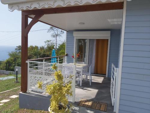 a porch of a blue house with a table at Les Gîtes Kajou in Bouillante