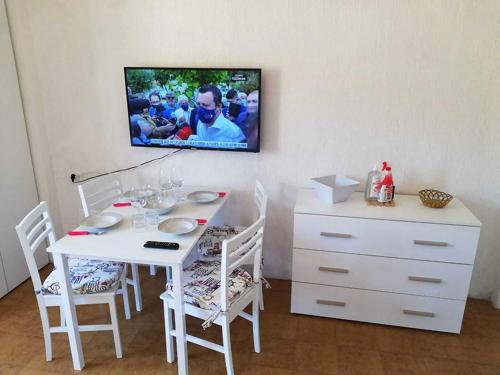 a white table with chairs and a tv on a wall at Stella Maris in Campese