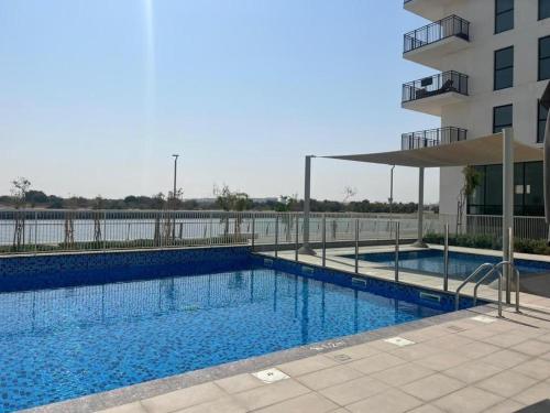 2 bedroom apartment Wabi Sabi in Yas في أبوظبي: مسبح كبير بجانب مبنى