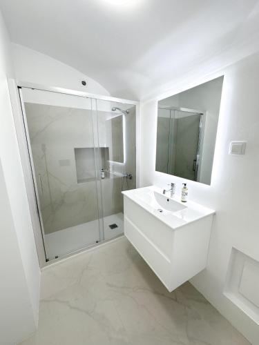 a white bathroom with a sink and a shower at Bombarda 15 Evora in Évora