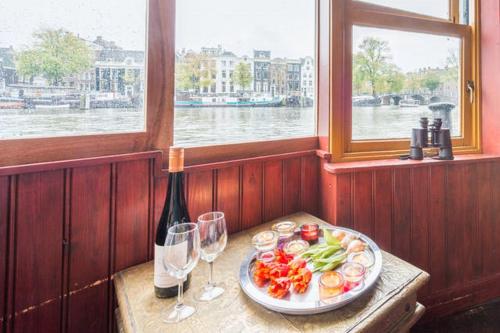 アムステルダムにあるHouseboat Amstel River Studioのテーブル(一皿の食べ物とワイングラス付)