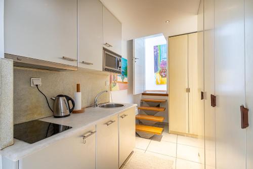 kuchnia z białymi szafkami i zlewem w obiekcie Arthome Acropolis View w Atenach