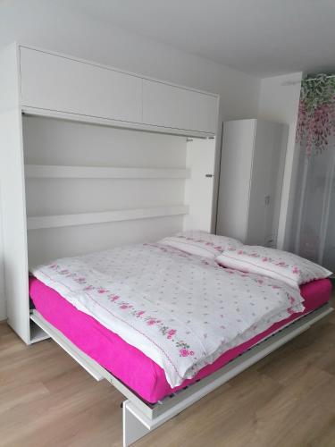 a white bed in a room with pink sheets at Apartmán Alicante in Dunajská Streda