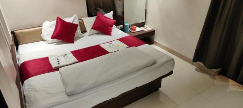 a bed in a hotel room with red and white pillows at Hotel Anand Palace in Shirdi