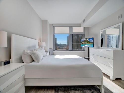 biała sypialnia z łóżkiem i telewizorem w obiekcie Global Luxury Suites at Reston w mieście Reston