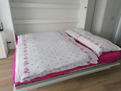 uma cama com cobertores e almofadas cor-de-rosa e brancos em Apartmán Alicante em Dunajská Streda