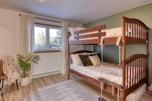 a bedroom with two bunk beds and a window at Spacious cottage in forest with spa in La Macaza