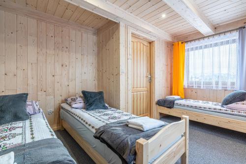 two beds in a room with wooden walls at Domki na Wiyrchu in Biały Dunajec