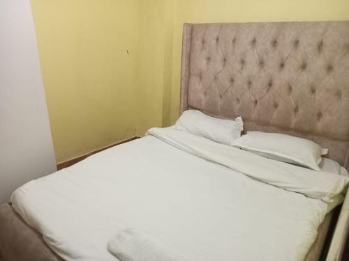 1 cama con sábanas blancas y almohadas en una habitación en Perpetual, en Nairobi
