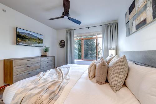 a bedroom with a white bed with a ceiling fan at Central 2BR with Prime Amenities in Whistler
