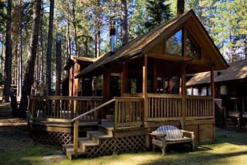 Cabaña de madera grande en el bosque con banco en Cold Springs Resort, en Camp Sherman