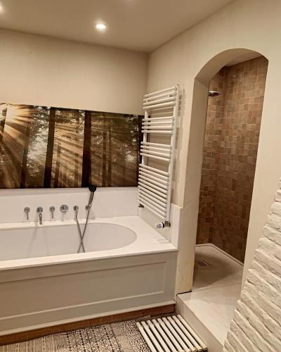 a large bathroom with a tub and a window at Hamiora wellness B&B in Deinze