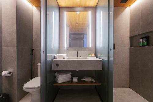 a bathroom with a sink and a toilet and a mirror at Ritz Barra de São Miguel in Barra de São Miguel