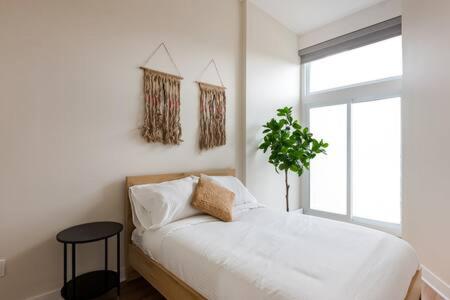 um quarto branco com uma cama e uma janela em Beautiful 2 BDR with Sofa Bed and Sky Light em Montreal