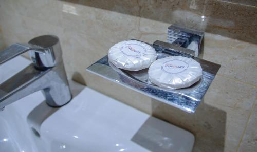 two white plates on a tray next to a sink at Hotel ByHours Las Américas in Bogotá