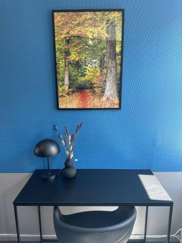 eine blaue Wand mit einem Schreibtisch mit einem Stuhl und einem Bild in der Unterkunft Room 7 On Pedestrian Street Sby - Free Parking in Sæby