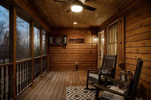 a porch of a log cabin with a ceiling fan at Shenandoah dog friendly cabin with river access, hot tub, fire pit, BBQ, outdoor dining in Shenandoah