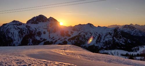 a snowy mountain with the sun setting over the mountains at Sonnleitn AlpinWell Appartment (Ski in&out + Wellness) in Hermagor