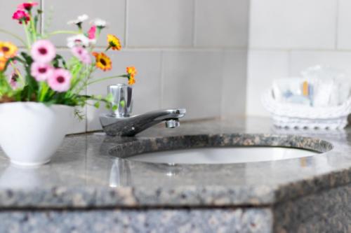 a bathroom sink with a vase of flowers on it at Hotel Minastur in Capitólio