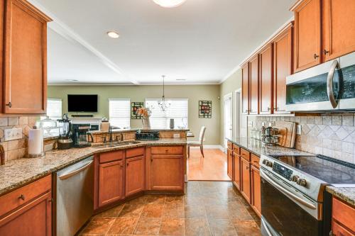 a large kitchen with wooden cabinets and a counter top at Spacious Phenix City Home about 9 Mi to Columbus! in Phenix City