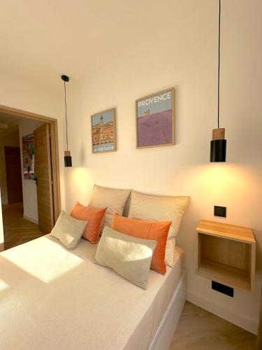 une chambre avec un lit avec des oreillers orange et blancs dans l'établissement MONACO # MENTON - 6 PERSONS - 2 BEDROOMS - FULL RENOVATED - PRIVATE PARKING - FULL CLIM - HYPERCENTER - BEACH AND SUn, à Menton