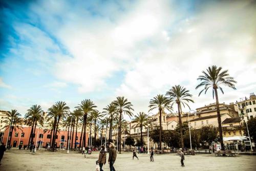un grupo de personas caminando por una plaza con palmeras en La Finestra sul cielo del porto antico di Genova en Génova