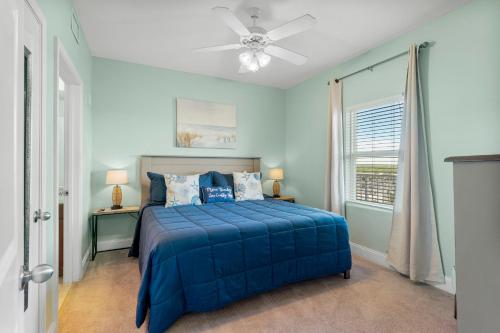 een blauwe slaapkamer met een bed en een plafondventilator bij Nautical Nest at Laketown Wharf #1019 by Nautical Properties in Panama City Beach