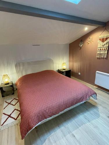 a bedroom with a bed with a red comforter at Charmant appartement in Béguey