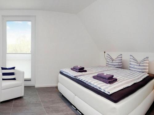 a white bedroom with a bed and a white chair at Ferienhaus am Yachthafen in Peenemünde in Peenemünde