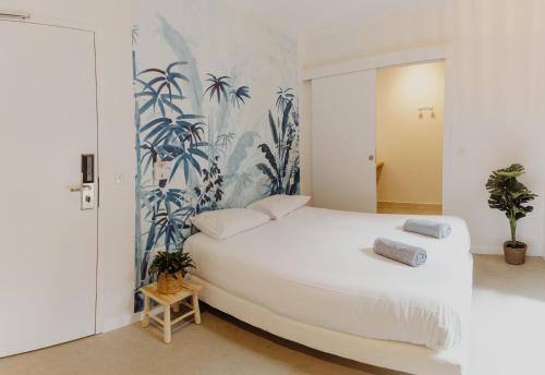 a bedroom with a large white bed with plants on the wall at HEJMO in Hossegor
