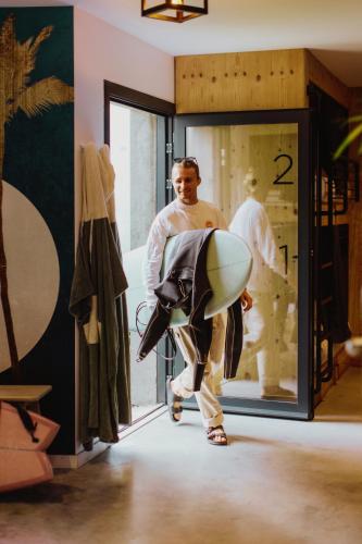 a man is carrying a surfboard in a room at HEJMO in Hossegor