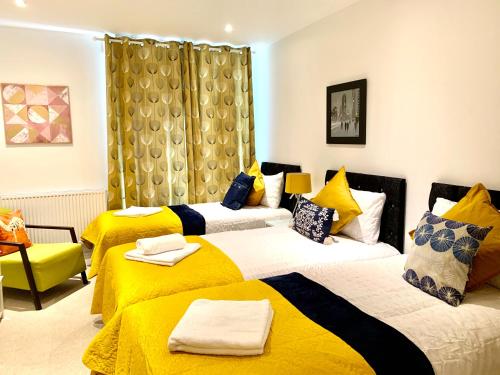 um quarto de hotel com duas camas com lençóis amarelos em Dockland Excel 2 Bedroom Apartment em Londres