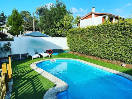 una piscina en un patio con 2 sillas al lado en La Casina de Rodiles en Liñero