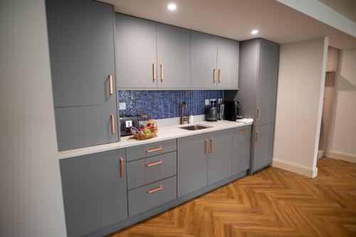 a kitchen with gray cabinets and a wooden floor at Kilkenny Suites in Kilkenny
