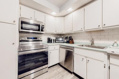 a kitchen with white cabinets and stainless steel appliances at Pico Mountain Perch, Unit B22 in Mendon