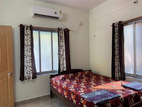 a bedroom with a bed and two windows at Royal Devbaug Holiday Home in Malvan