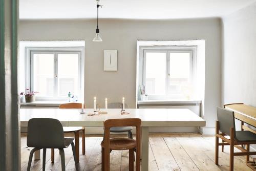 a dining room with a table and chairs and two windows at The architects' house in Stockholm