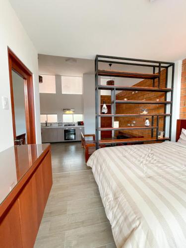 ein Schlafzimmer mit einem Bett und einem Schreibtisch sowie eine Küche in der Unterkunft Mono ambiente comfortable in Moyobamba