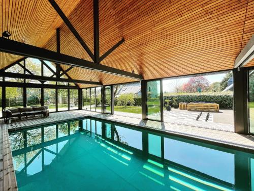 een binnenzwembad in een huis met een houten plafond bij Gîtes du Domaine du Grenier in Yffiniac