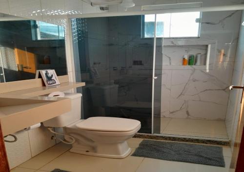 a bathroom with a toilet and a glass shower at Casa Espetacular Com Piscina in Cabo Frio