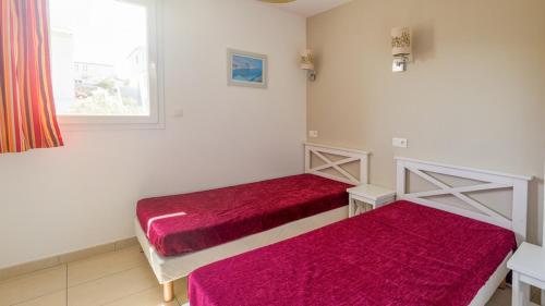 Cette chambre comprend 2 lits avec des draps rouges et une fenêtre. dans l'établissement Mini-villa alliance wifi proche ile rousse, à Belgodère