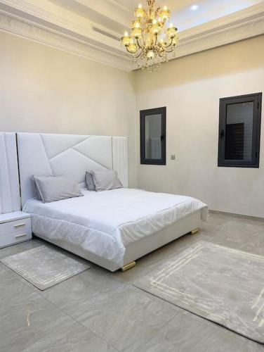 ein Schlafzimmer mit einem weißen Bett in einem Zimmer mit einem Kronleuchter in der Unterkunft Villa Artemis (Ground Floor) in Rejiche