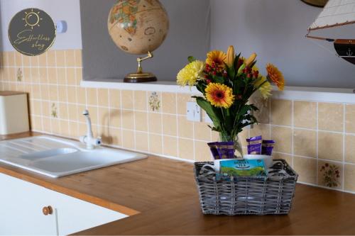 a kitchen counter with a vase of flowers on it at Leeward House -Solent views, Parking,High Street Location, Couples, Groups, Families and Professionals Welcome in Lymington