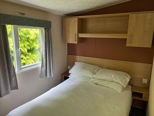 a small bedroom with a bed and a window at Lovely Caravan At Lower Hyde Holiday Park, Isle Of Wight Ref 24001g in Shanklin