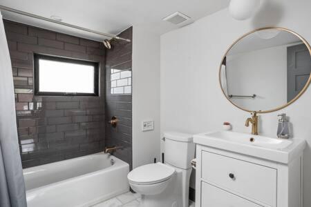 a bathroom with a sink and a toilet and a mirror at Modern Architect's Duplex by CozySuites in Indianapolis